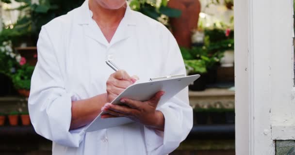 Female scientist writing on clipboard — Stock Video