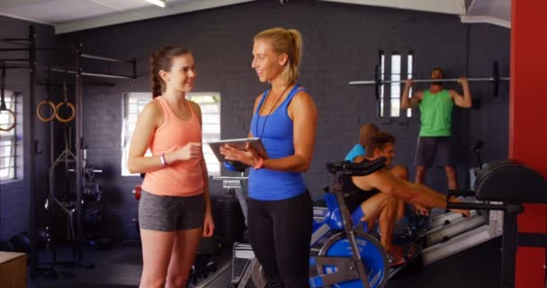 Treinador feminino interagindo com a mulher enquanto usa tablet digital — Vídeo de Stock