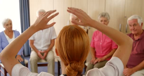 Терапевт, помогающий пожилым людям с упражнениями — стоковое видео