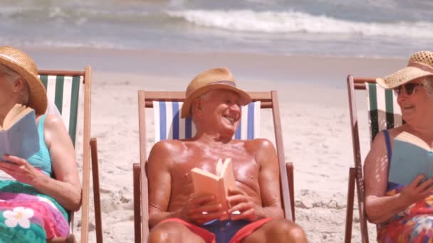 Starszy przyjaciele siedząc w fotelu plaży — Wideo stockowe