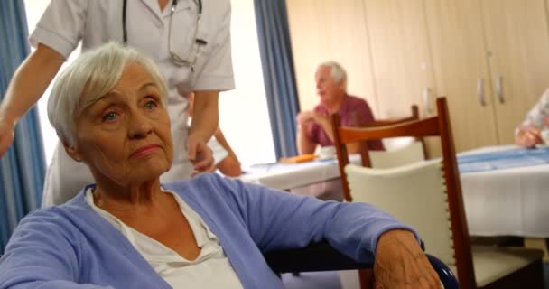 Доктор разговаривает со старшей женщиной, сидящей в инвалидном кресле — стоковое видео
