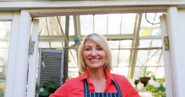 Mature woman standing at the entrance of greenhouse — Stock Video