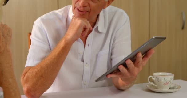 Старший мужчина с цифровым планшетом взаимодействует со старшей женщиной — стоковое видео