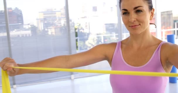 Sportvrouw stretching een gele band — Stockvideo