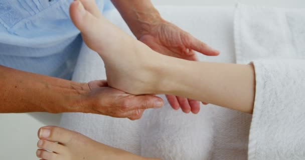 Терапевт массирует ноги пациентки — стоковое видео