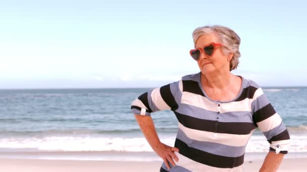 Літня жінка стоїть на пляжі — стокове відео