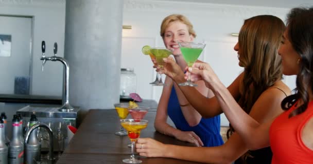 Happy friends are sitting on counter and holding cocktail — Stock Video