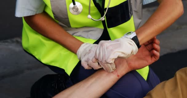 Medical technician taking the pulse of wounded person — Stock Video