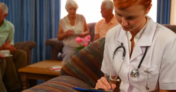 Médico feminino com pessoas idosas em segundo plano — Vídeo de Stock