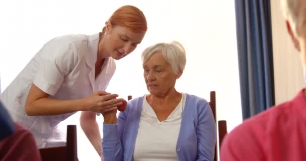 Terapeuta asistiendo a personas mayores con ejercicio — Vídeo de stock