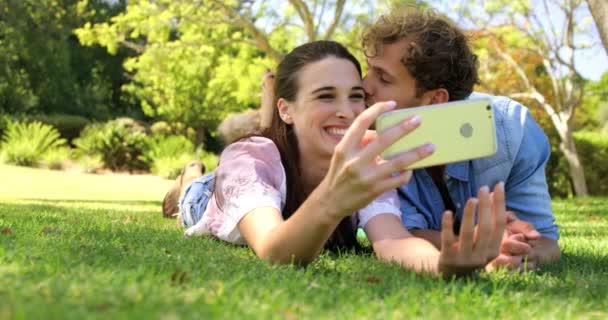 Para, leżąc na trawie biorąc selfie — Wideo stockowe