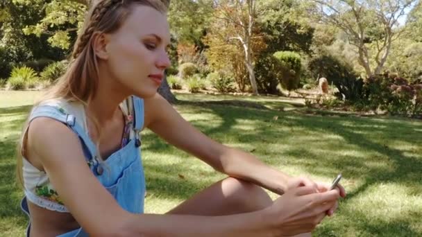 Красива дівчина надсилає текст у парку — стокове відео