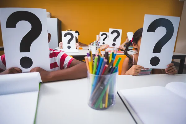 Schoolkinderen die betrekking hebben op hun gezicht met vraagteken teken — Stockfoto