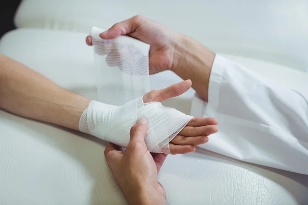 Gyógytornász kötszer felhelyezése sebesült kezét — Stock Fotó
