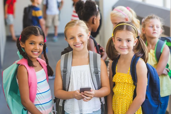 School kids standing in corridor with mobile phone — Stock Photo, Image