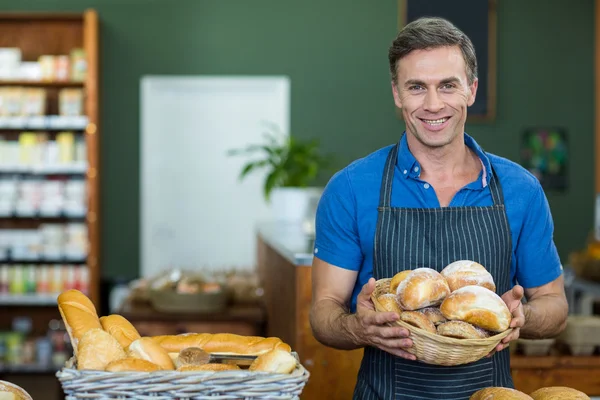 Portrait of male staff holding a basket of bread — Stock Photo, Image