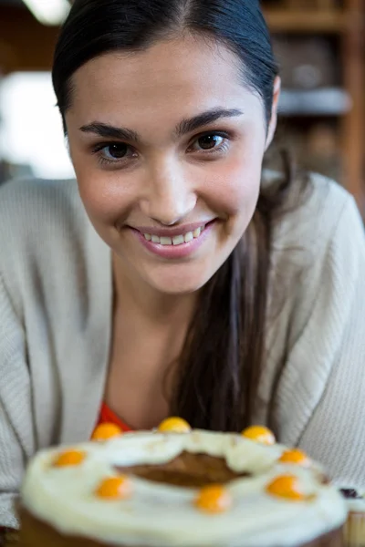 Χαμογελαστή γυναίκα με κέικ μπροστά — Φωτογραφία Αρχείου