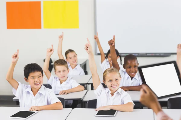 Des écoliers lèvent la main en classe — Photo