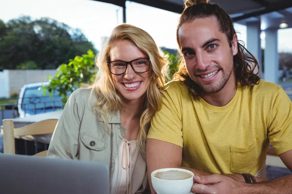 Casal jovem usando laptop na cafetaria — Fotografia de Stock