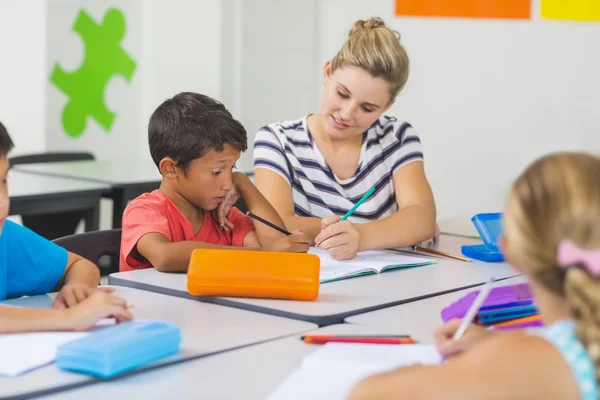 Insegnante aiutare i bambini con i loro compiti in classe — Foto Stock