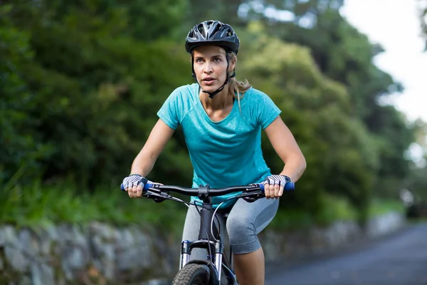 Женщина на велосипеде по дороге — стоковое фото