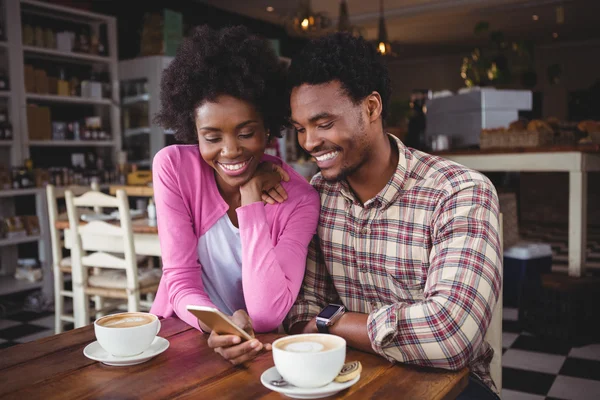 Pareja joven usando teléfono móvil en la cafetería — Foto de Stock