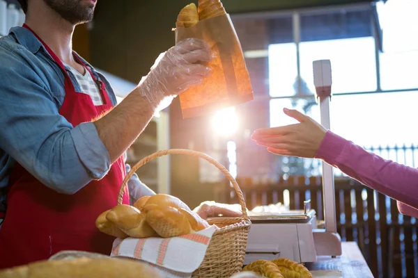 Staff giving packet bread to customer — Stock Photo, Image