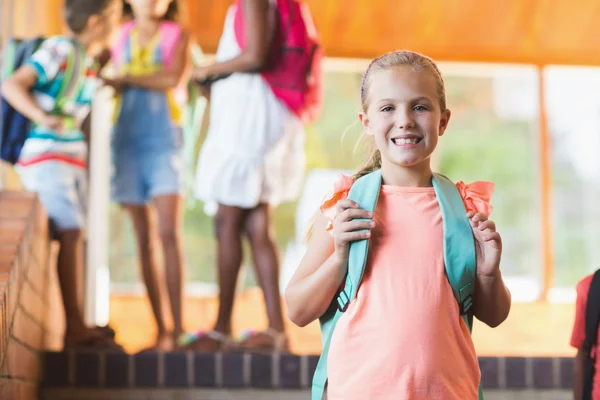 Glimlachend schoolmeisje staande op de trap — Stockfoto