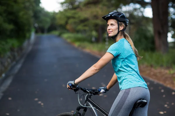 Mujer de pie con bicicleta de montaña en la carretera abierta — Foto de Stock