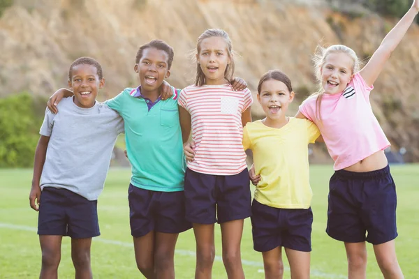 Niños de la escuela de pie con los brazos alrededor —  Fotos de Stock