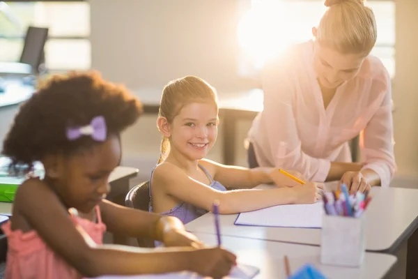 Lärare att hjälpa barnen med deras läxor i klassrummet — Stockfoto