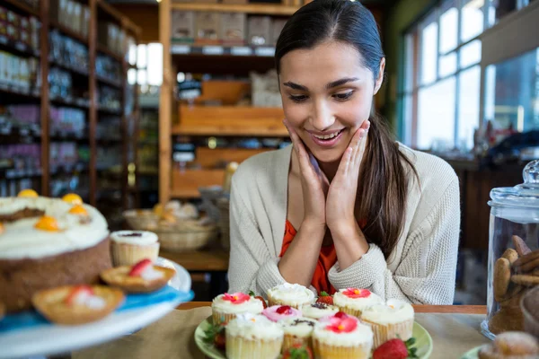 Lycklig kvinna som tittar på cupcakes — Stockfoto
