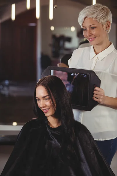Cabeleireiro mostrando mulher seu corte de cabelo no espelho — Fotografia de Stock