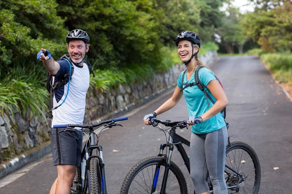 Атлетическая пара с горным велосипедом указывает на расстоянии — стоковое фото