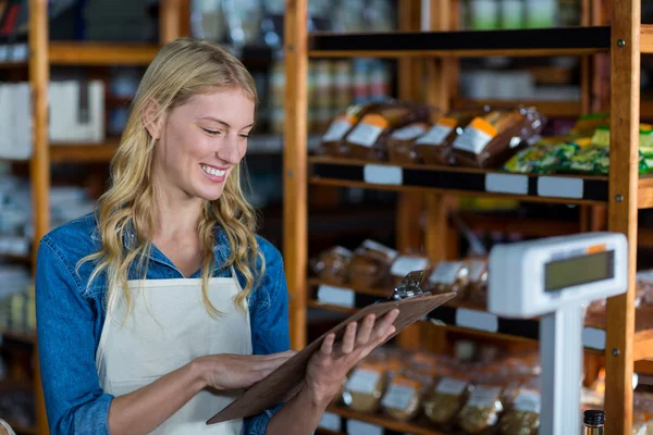 Smiling female staff looking at clipboard — Stock Photo, Image