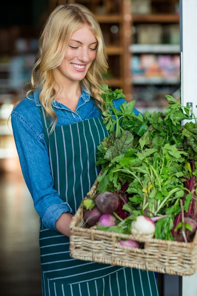 Female staff holding a basket of fresh vegetables — Stock Photo, Image