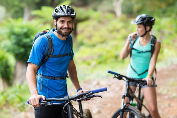 Homem de pé com bicicleta de montanha na floresta — Fotografia de Stock