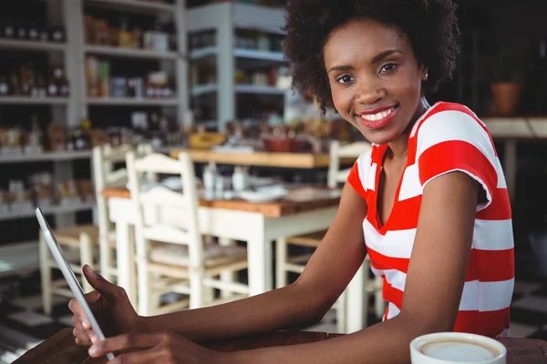 Mujer sonriente usando tableta digital en la cafetería —  Fotos de Stock