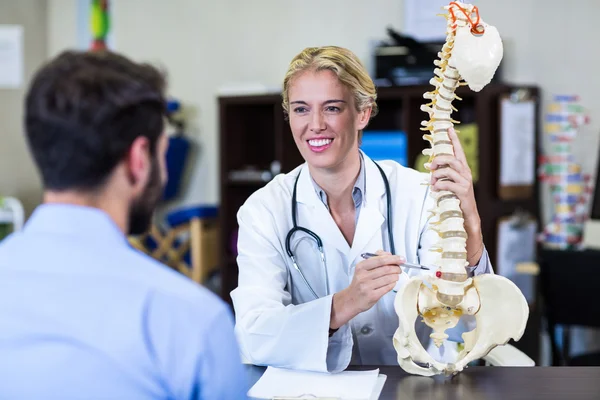 Fisioterapeuta explicando o modelo da coluna vertebral para o paciente — Fotografia de Stock