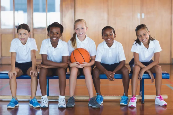 Retrato de crianças da escola sentadas na quadra de basquete — Fotografia de Stock