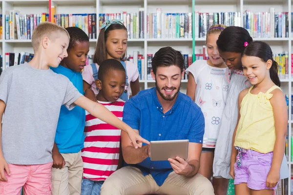 Вчитель навчає дітей на цифровому планшеті в бібліотеці — стокове фото