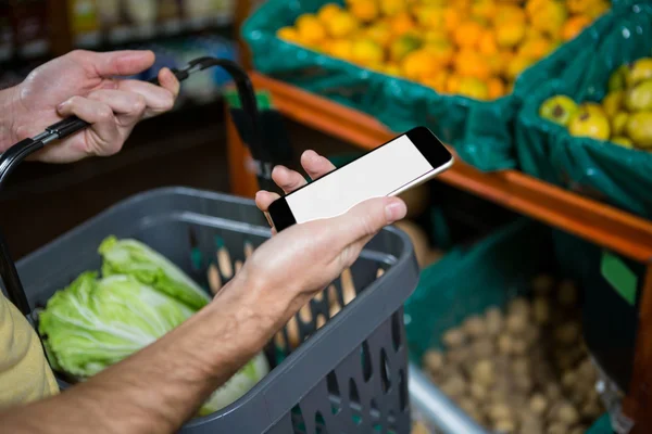 Homem verificando telefone compra de legumes — Fotografia de Stock
