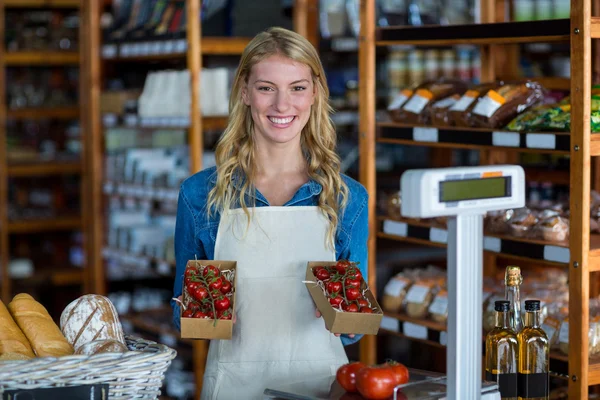 Sonriente personal femenino sosteniendo caja de tomate cherry — Foto de Stock