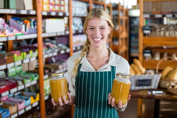 Női alkalmazottak gazdaság üvegek méz szupermarketben — Stock Fotó