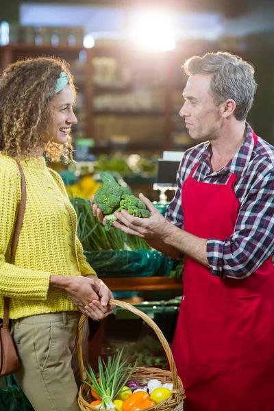 Personal masculino sonriente ayudando a una mujer con compras de comestibles — Foto de Stock