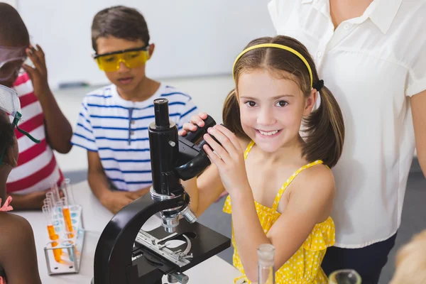 Школьница держит микроскоп в лаборатории — стоковое фото