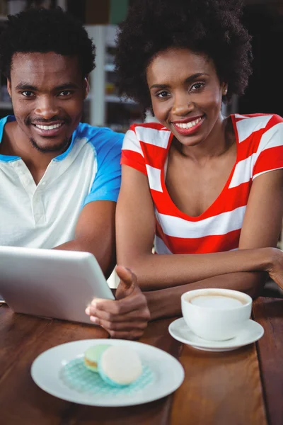 Retrato de pareja sonriente usando tableta digital en la cafetería — Foto de Stock