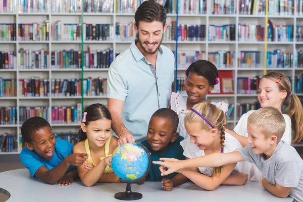 Alumnos y profesores mirando el globo en la biblioteca —  Fotos de Stock