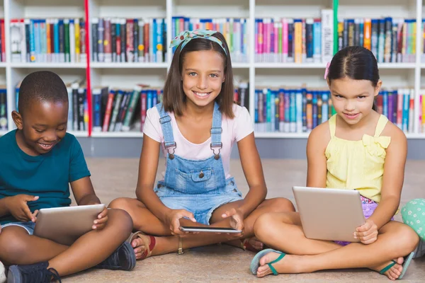 Schüler sitzen mit digitalem Tablet in Bibliothek auf dem Boden — Stockfoto