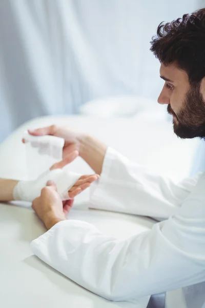 Fisioterapeuta poniendo vendaje en la mano lesionada —  Fotos de Stock